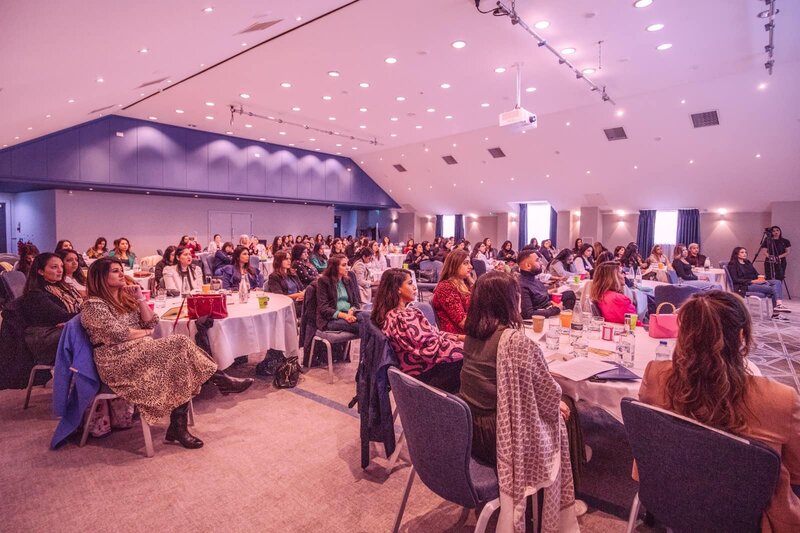 Women attending SHINE & RISE London 2026 seated at round tables during a women’s empowerment mindset event focused on business and motherhood.