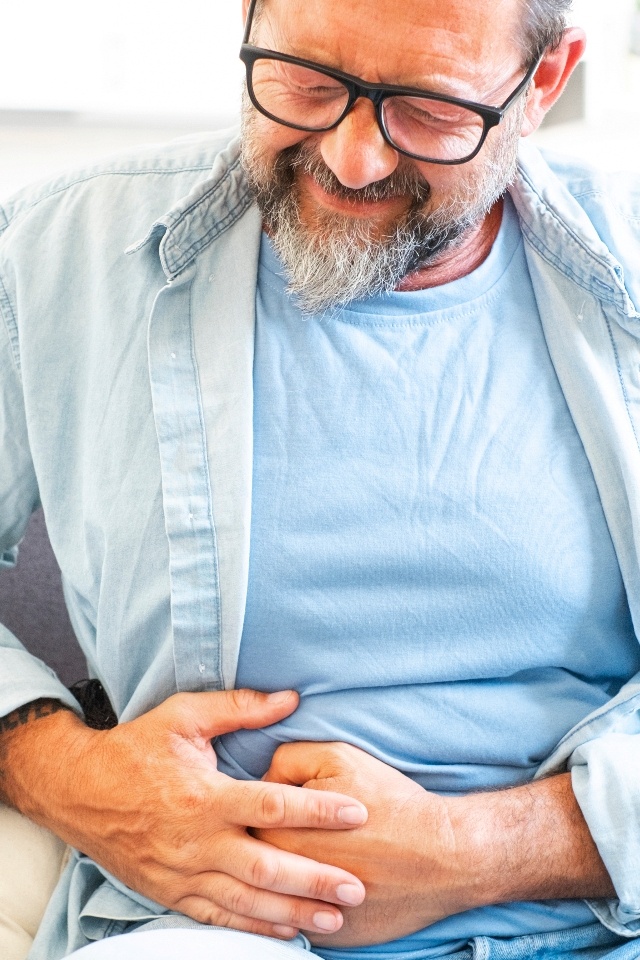 Man experiencing abdominal discomfort associated with digestive symptoms 