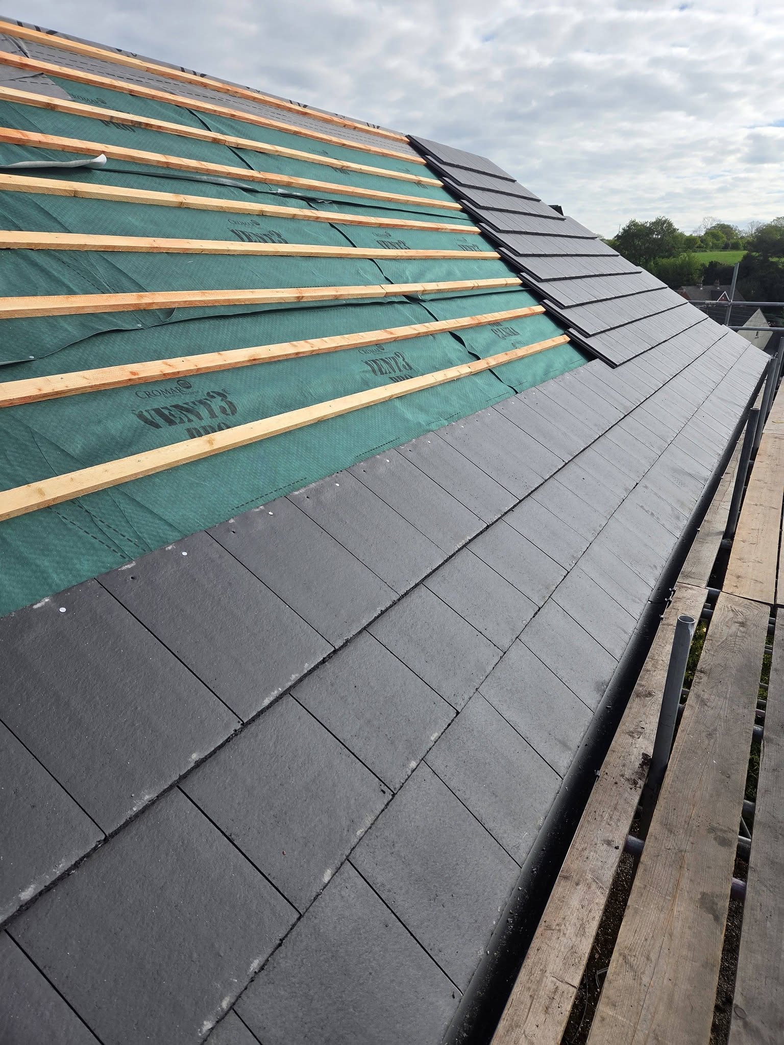 New grey slate roof being laid on breathable membrane and battens