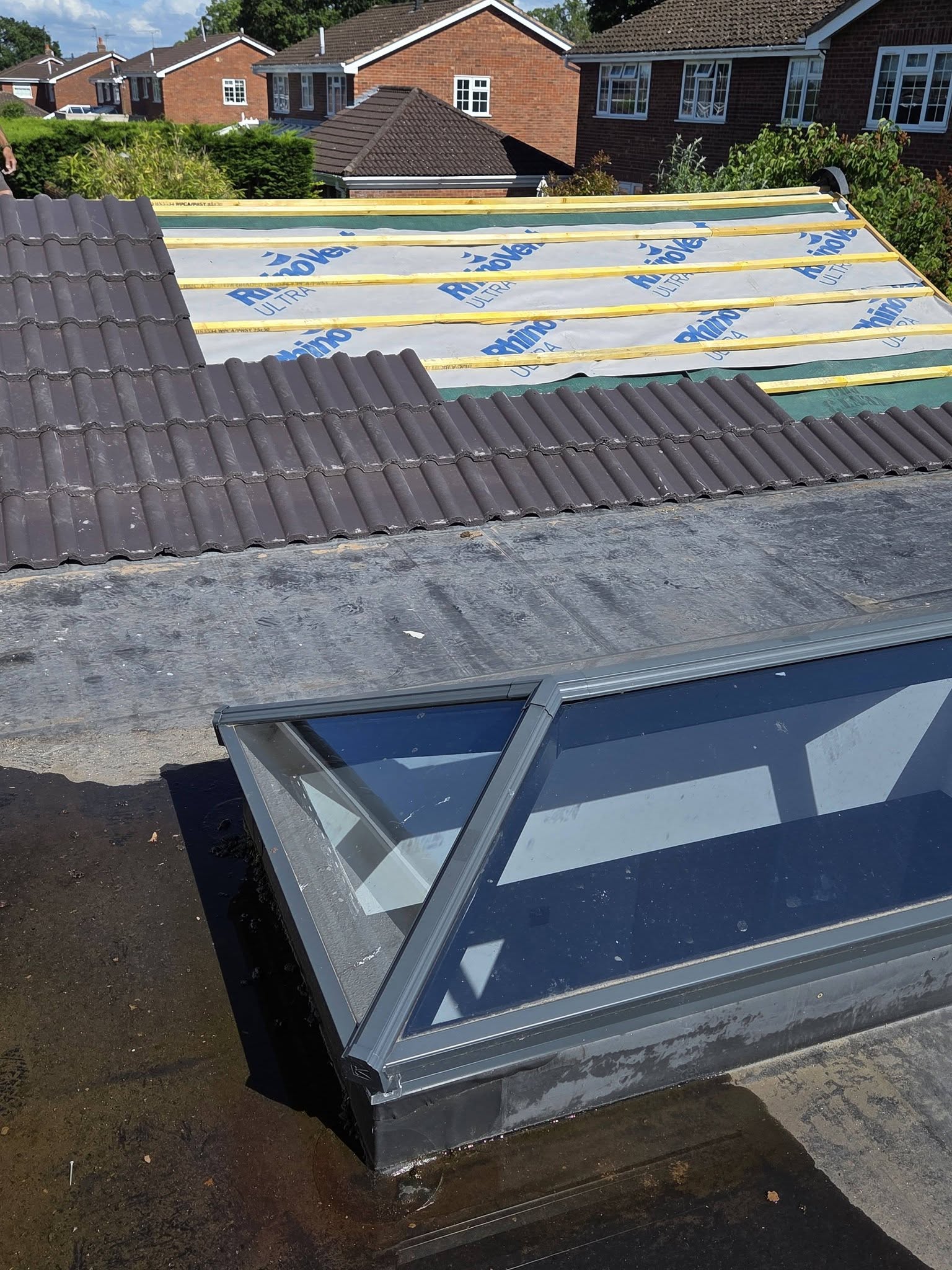 Flat roof with a glazed roof lantern fitted alongside a new tiled pitched roof