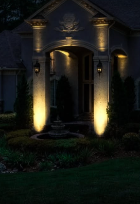 Warm uplights highlighting entrance columns and garden planting