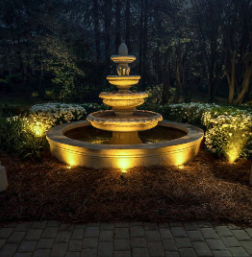 Warm lighting around a tiered garden fountain