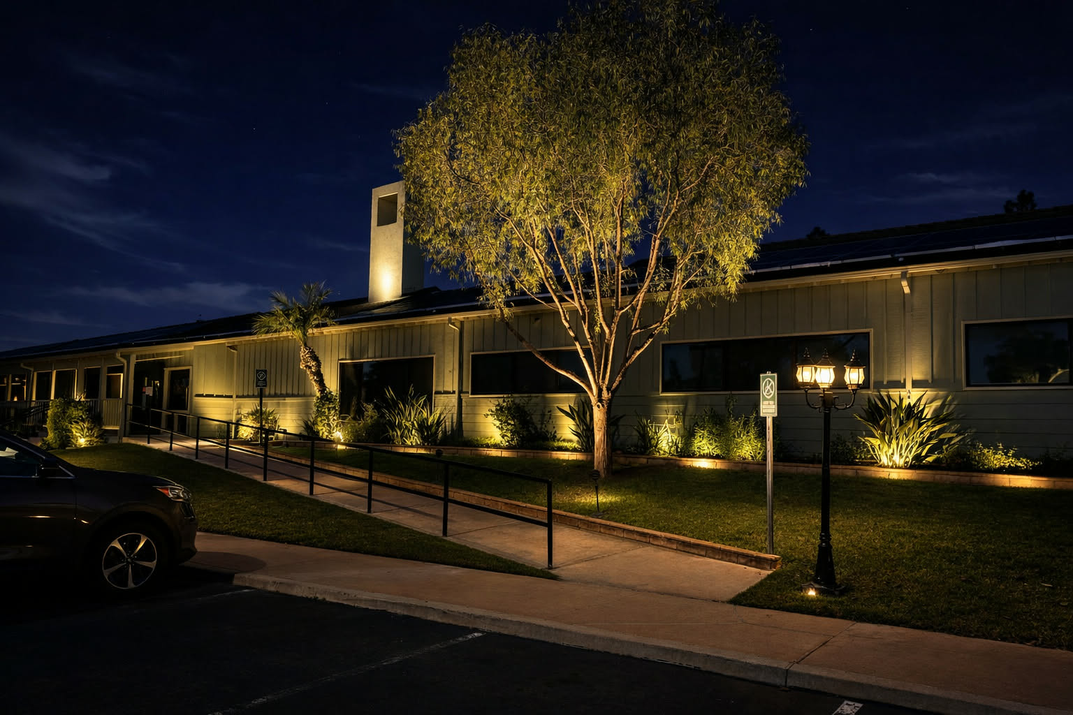 Tree and planting uplights along an outdoor building walkway