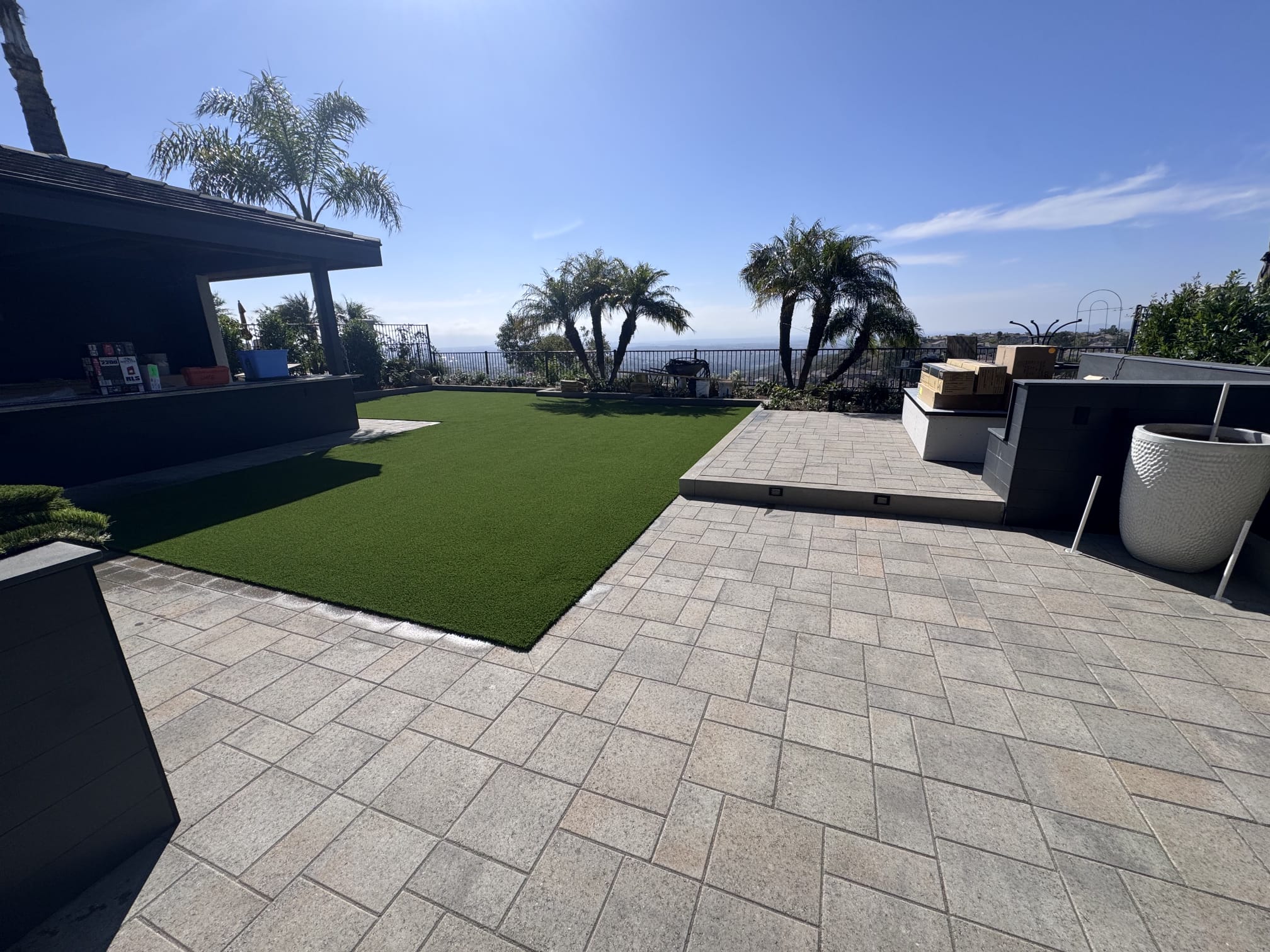 Artificial turf incorporated beside an expansive paver patio