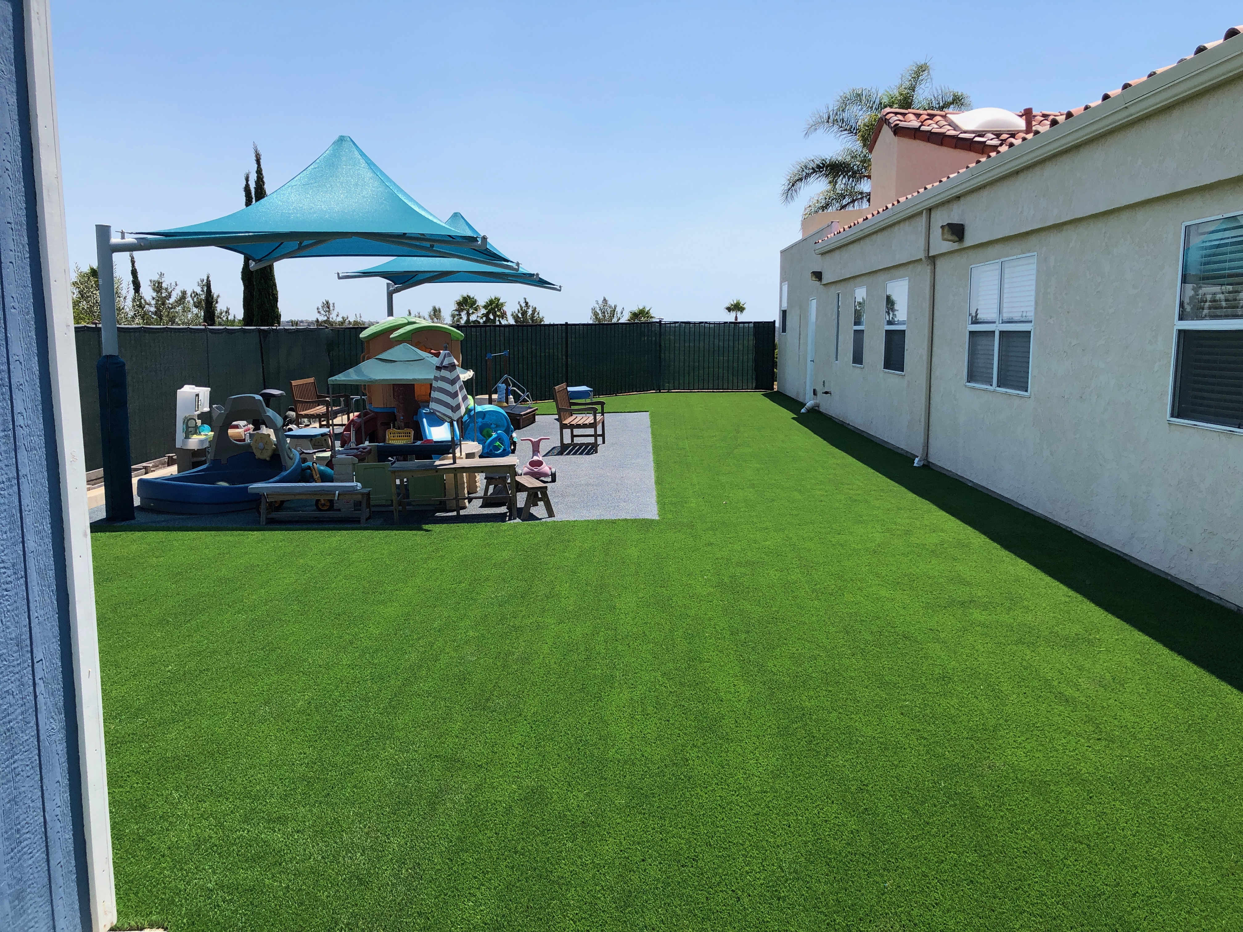 Artificial turf play area beside outdoor shade structures