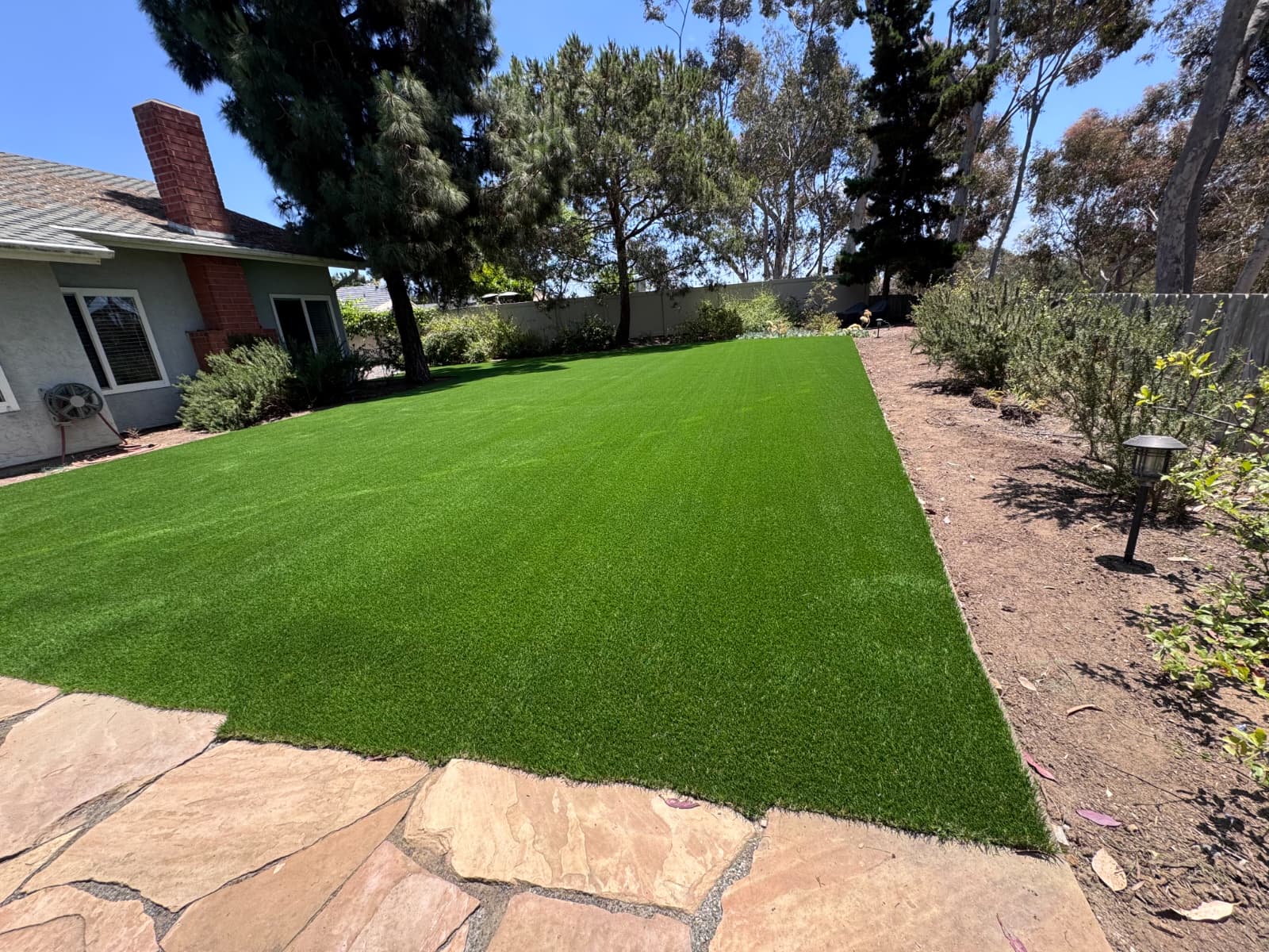 Residential backyard synthetic turf with planting beds and open area