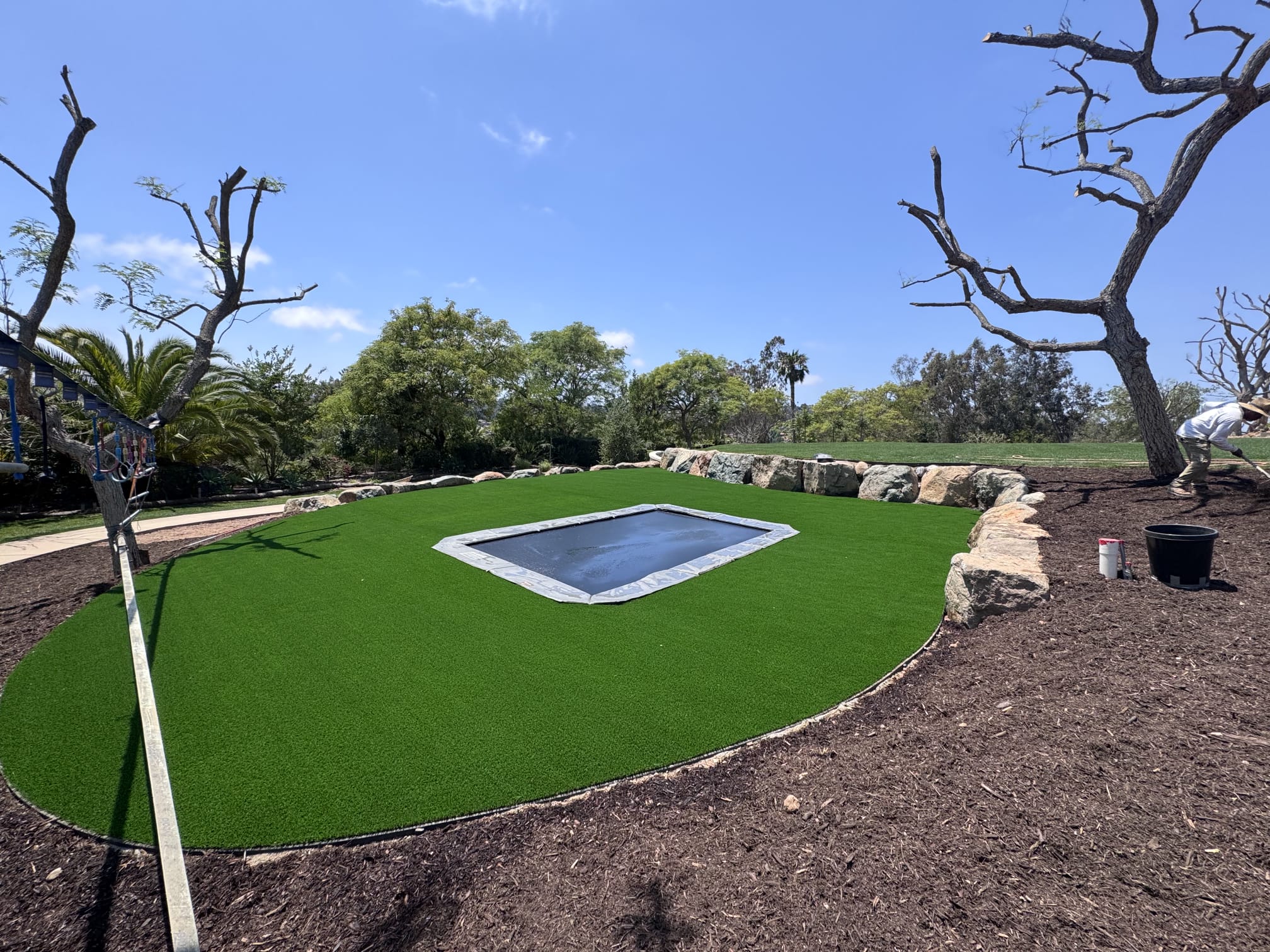 Large recreational turf area with in-ground trampoline and boulders