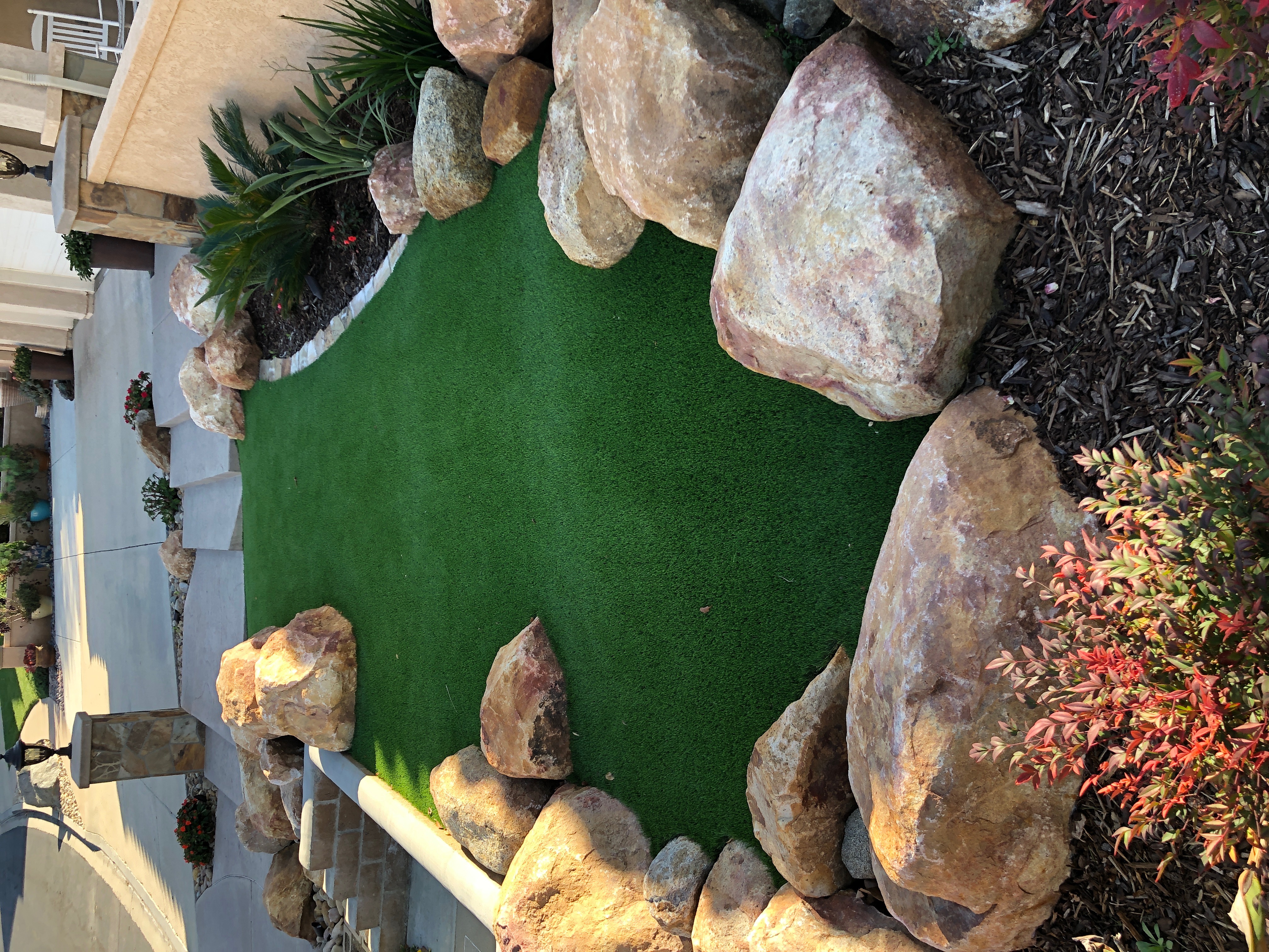 Compact artificial turf design integrated with boulders, planting, steps and landscape lighting