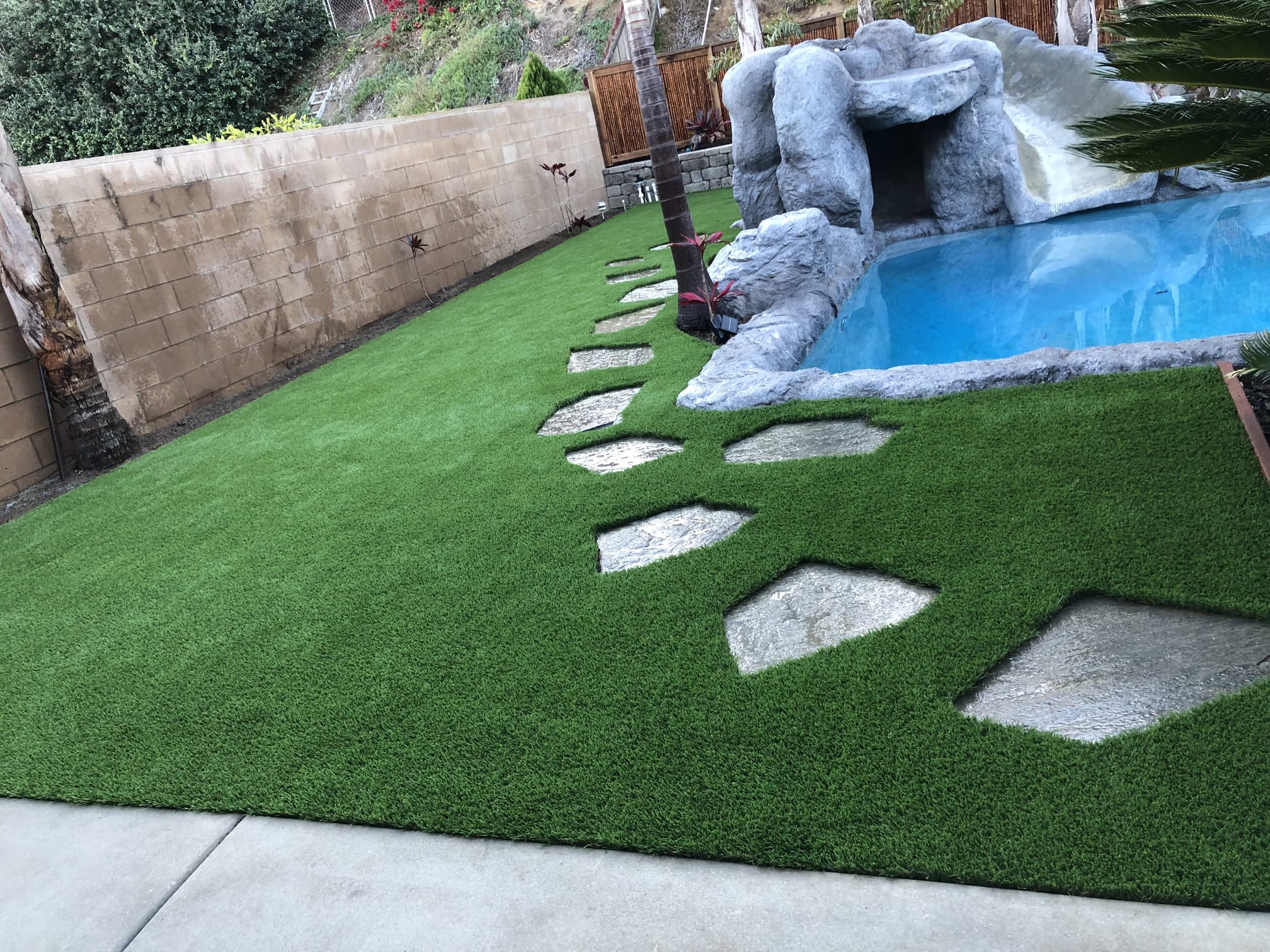 Compact artificial turf area integrated with boulders and a water feature