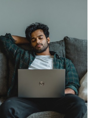 Man sitting on a couch with a laptop during an online counselling session at home, illustrating accessible emotional support through online counselling sessions in South Africa.