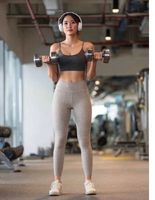 Woman standing in a gym holding dumbbells, illustrating safe return to exercise after Vaser liposuction recovery Woman standing in a gym holding dumbbells, illustrating safe return to exercise after Vaser liposuction recovery