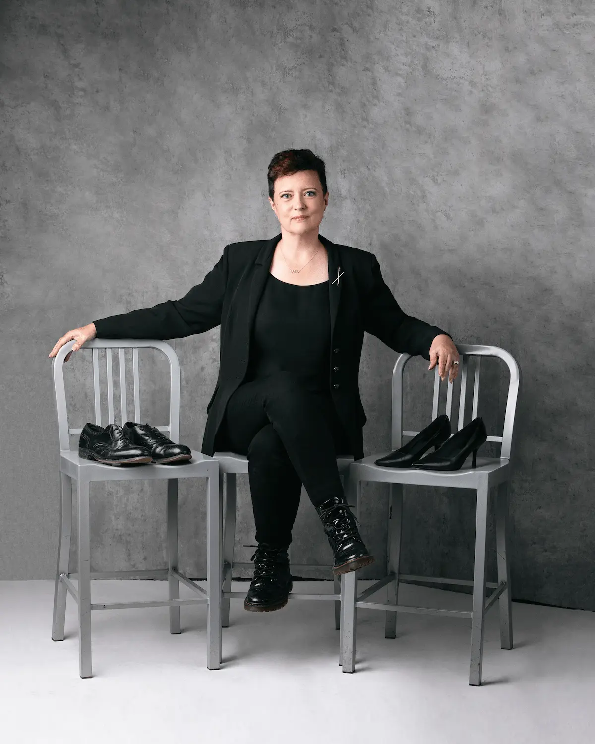Vanessa Cardenas seated between two chairs with men's shoes and women's shoes, representing couples relationship coaching in Westchester County, New York