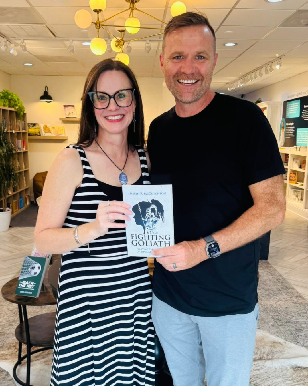 Jesslyn McCutcheon holding her book, Fighting Goliath, with Brian Dixon