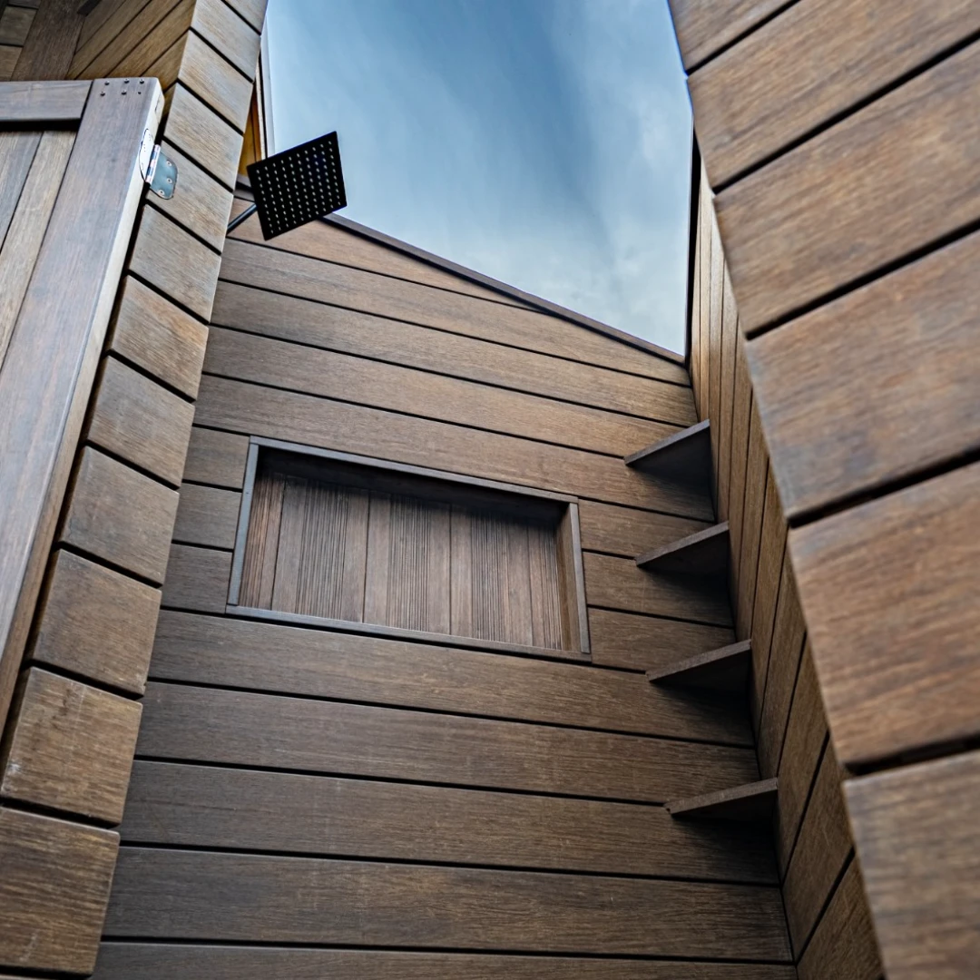 Outdoor rooftop or deck area with horizontal wood siding acting as a privacy wall, featuring a globe light fixture and small stool.