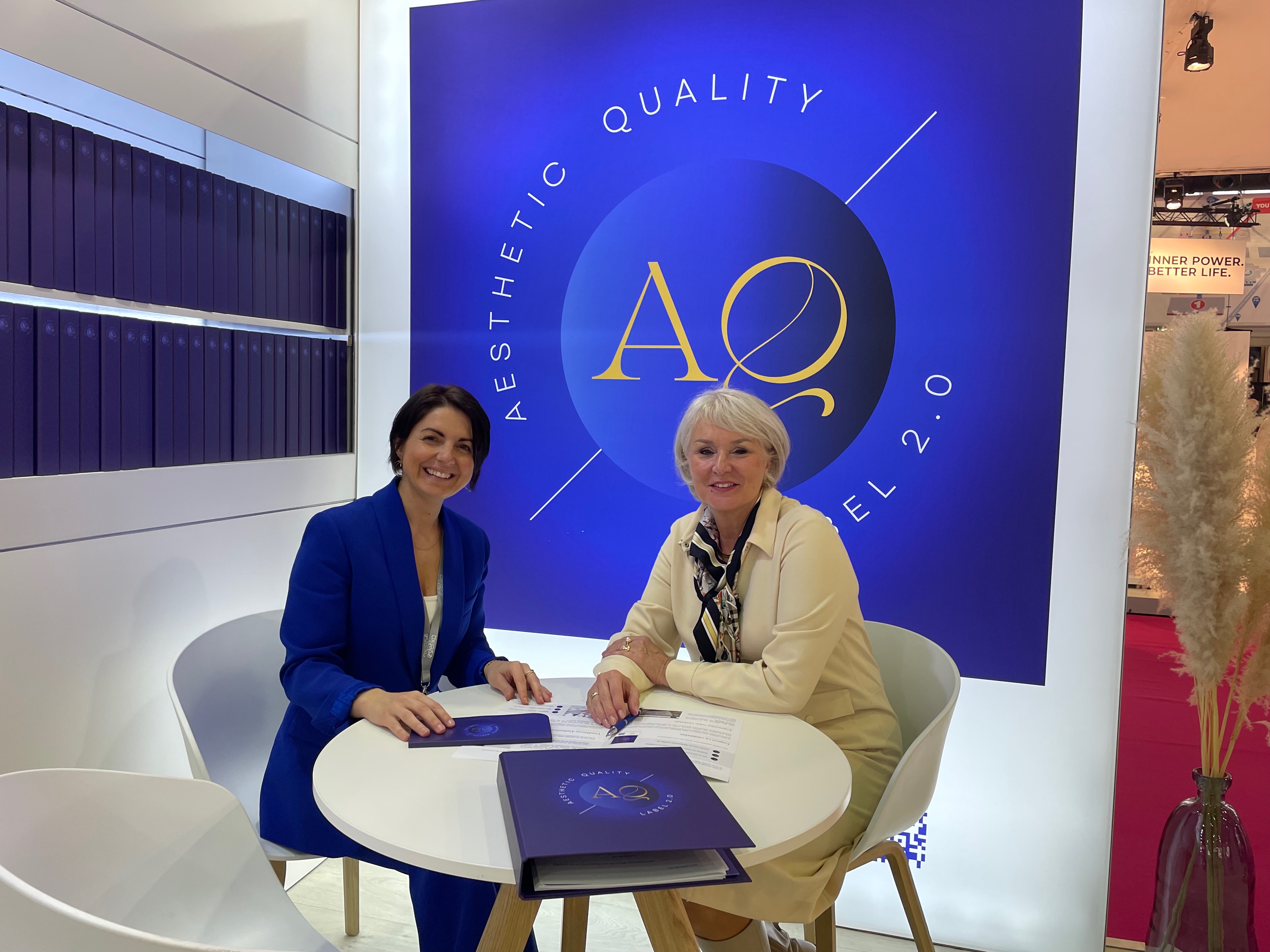 Esthéticienne fière de tenir sa plaquette Aesthetic Quality dans son institut