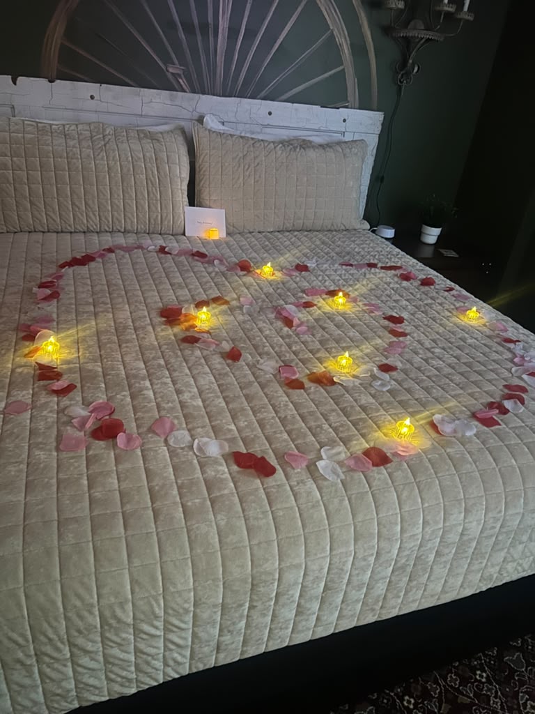 A suite bed set with a heart of rose petals and flameless candles for a celebrating guest