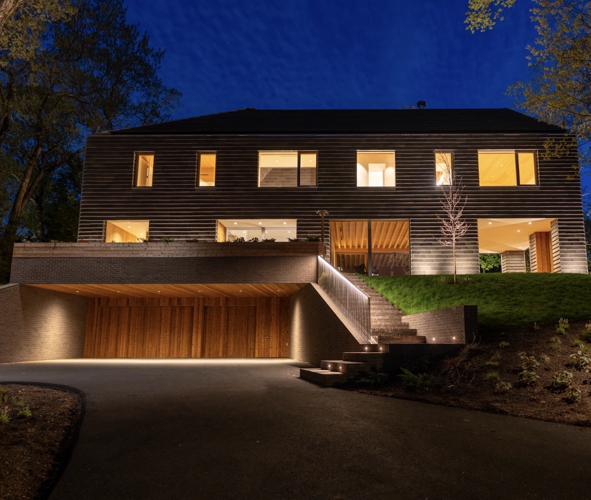 Modern house with layered exterior and stair lighting at night