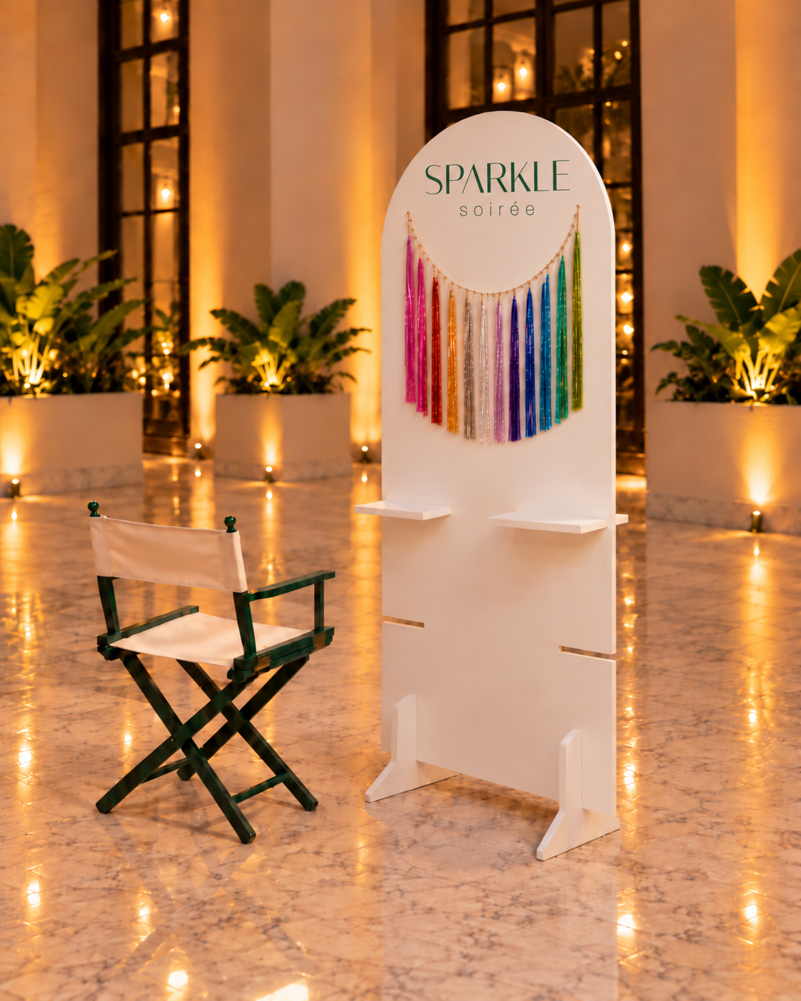 Le Sparkle Stand : une arche blanche avec ses sparkles en arc de couleurs, et une chaise verte à côté, dans une salle de réception.
