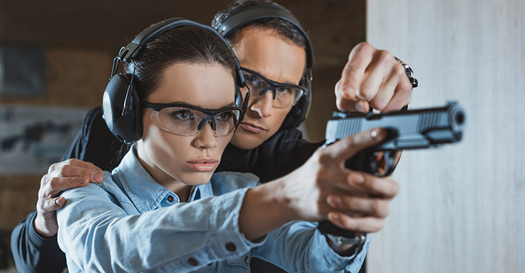 Instructor coaching a student on pistol fundamentals at the range