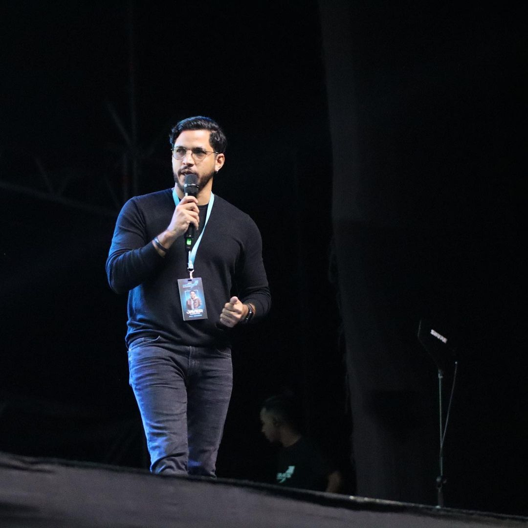 Persona en escenario dando una charla con micrófono