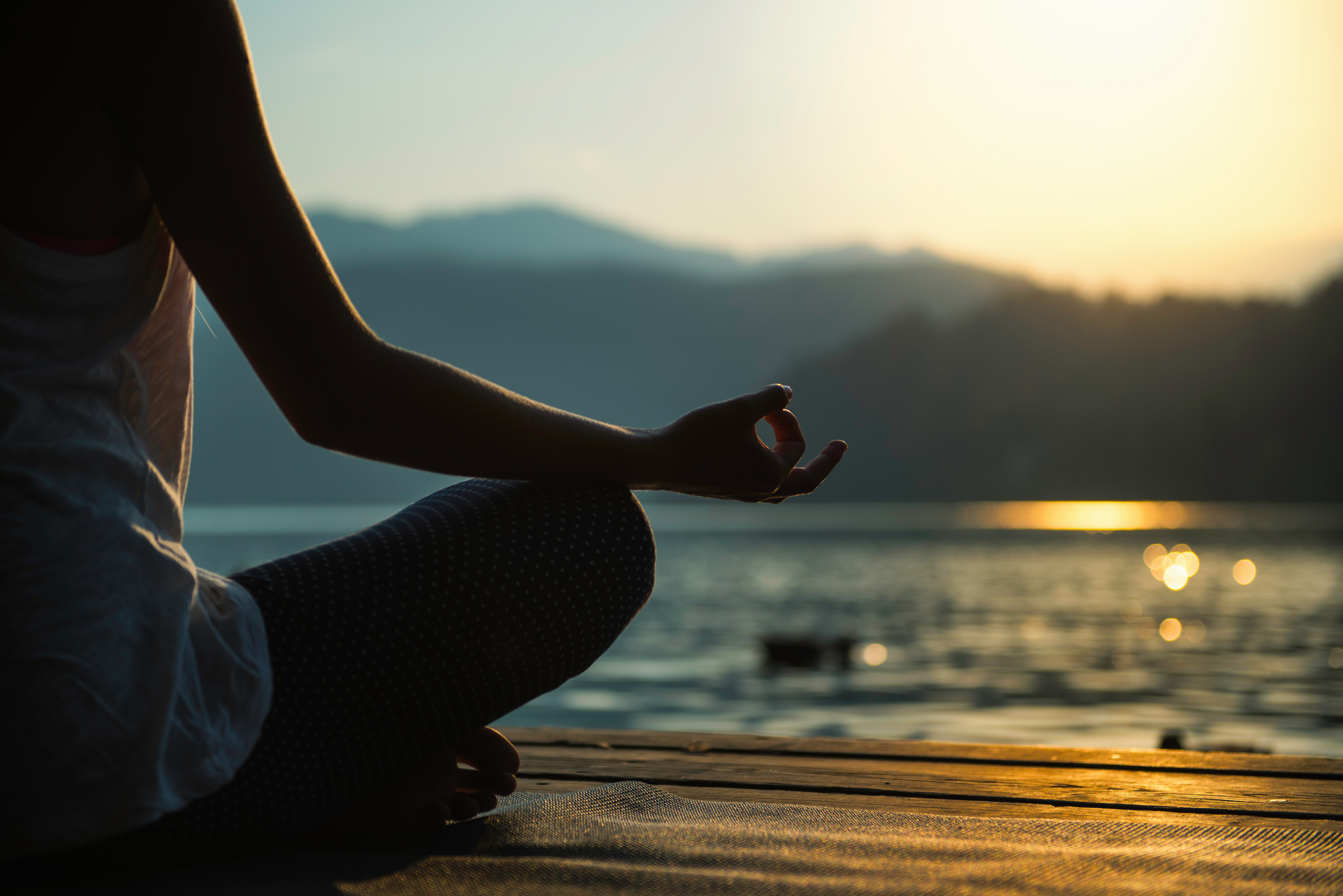 woman meditating by a lake