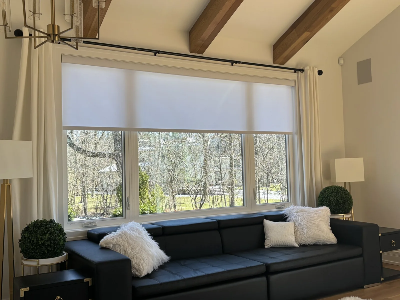 White light-filtering roller shades over a wide living room window