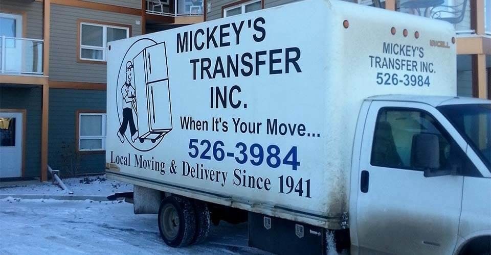 Mickey’s Transfer Inc white cube van parked in front of a three storey apartment building