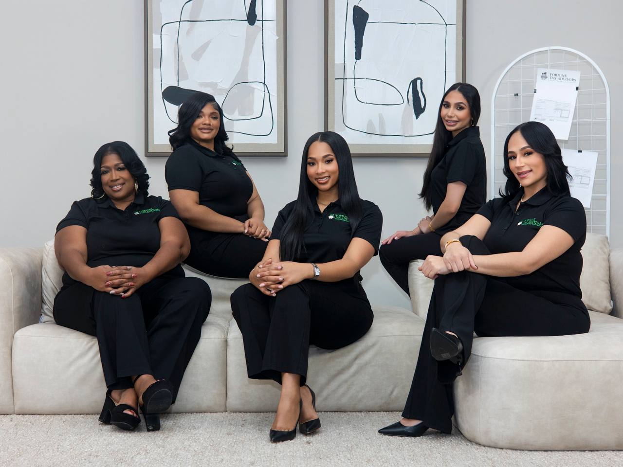 Five Fortune Tax Advisors team members smiling on a sofa in matching black polos