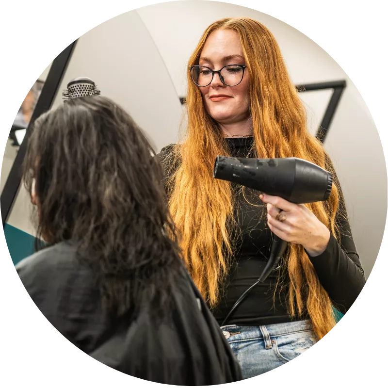 Hairstylist blow-drying client’s hair at Ten Sails Salons in Maryland.