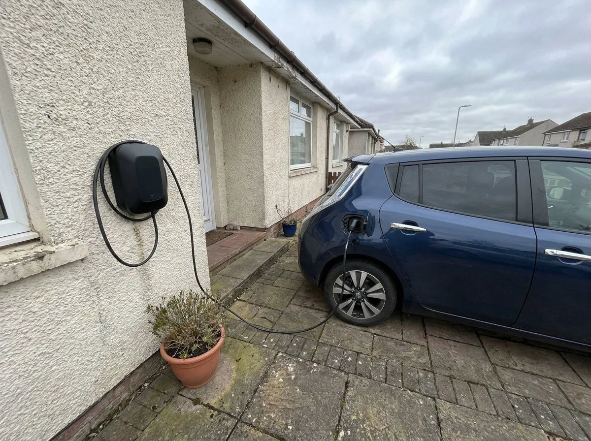 Wall-mounted home EV charger beside a parked electric car