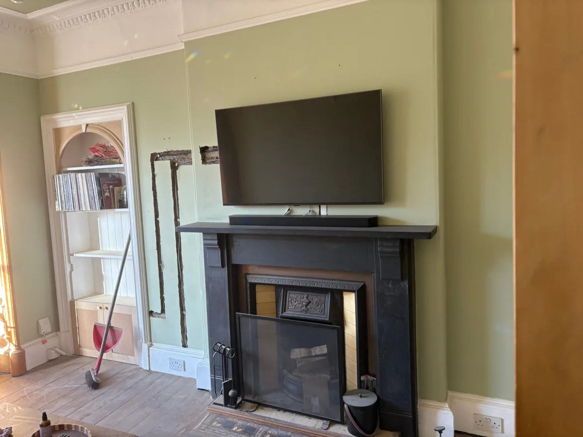 Living-room electrical work around a fireplace and fitted shelving
