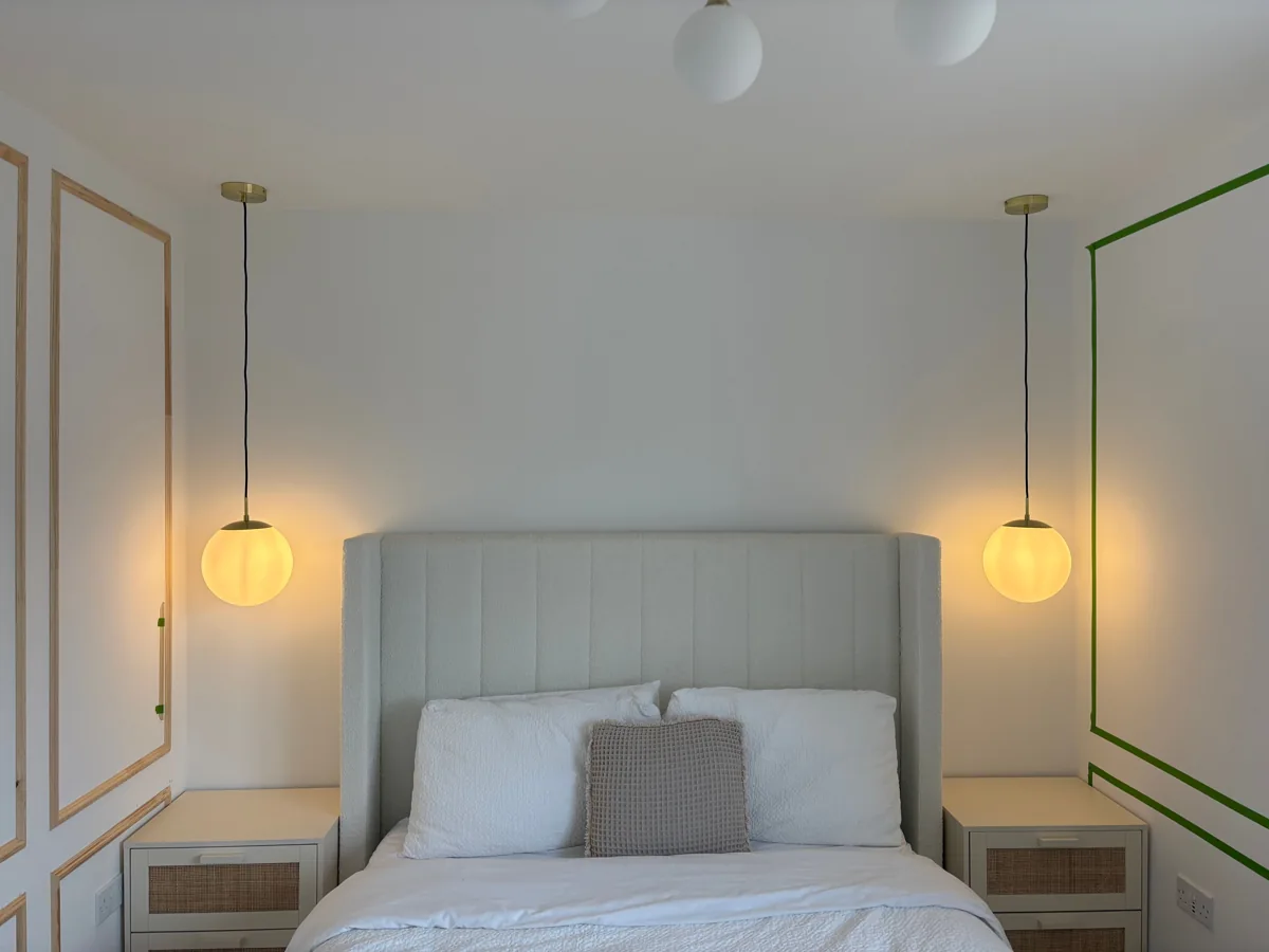 Warm bedside pendant lights in a panelled bedroom