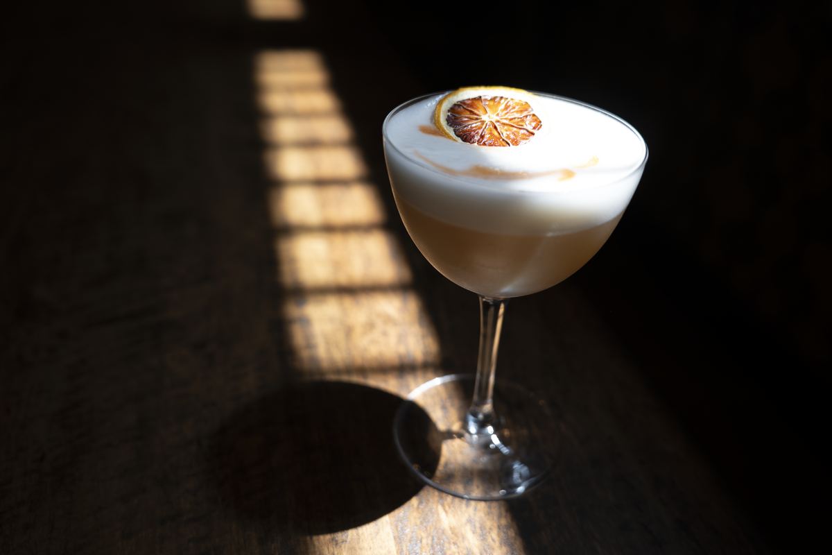 Frothy signature cocktail with citrus wheel