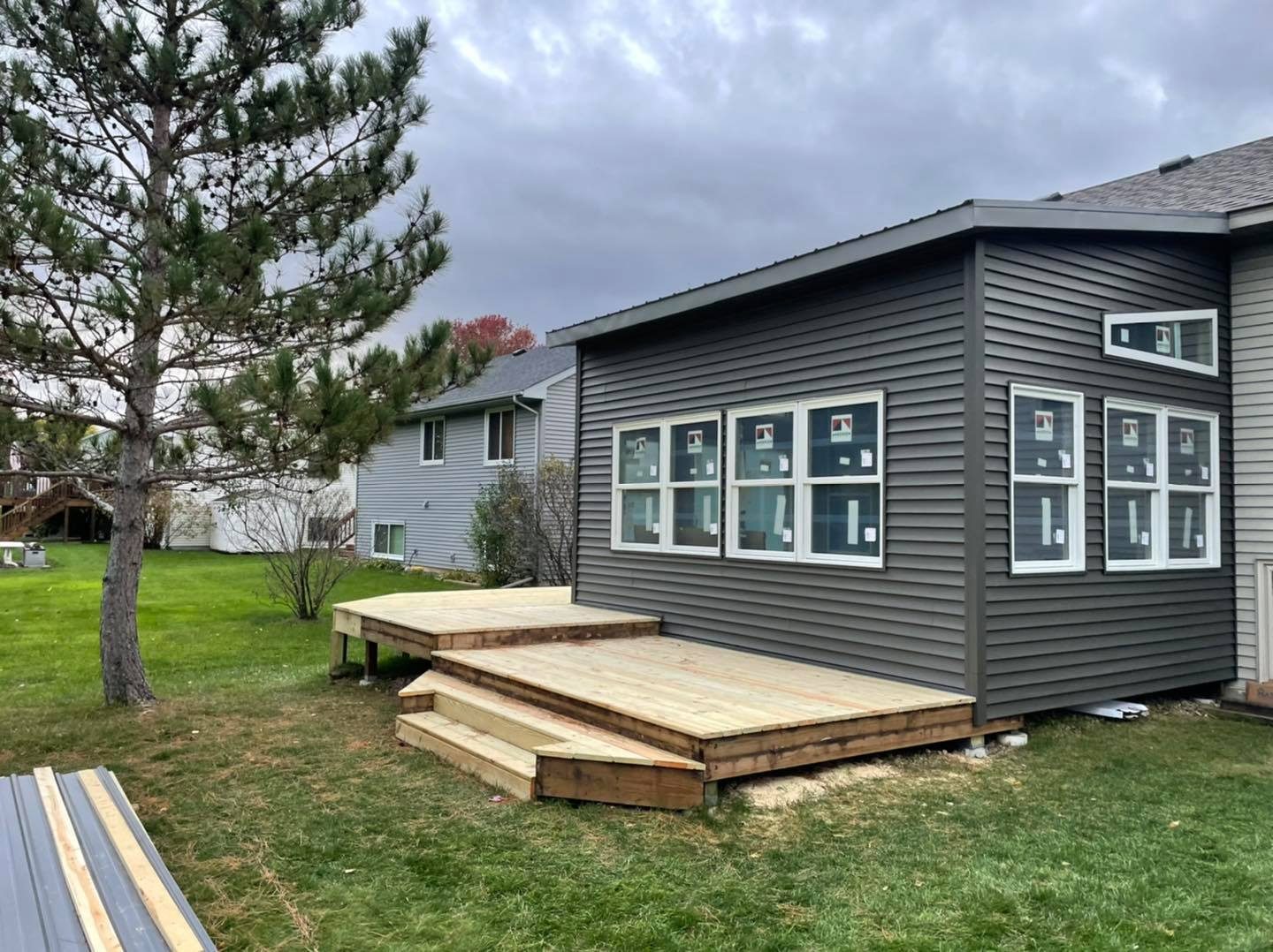 Home addition with gray siding, new windows and a deck