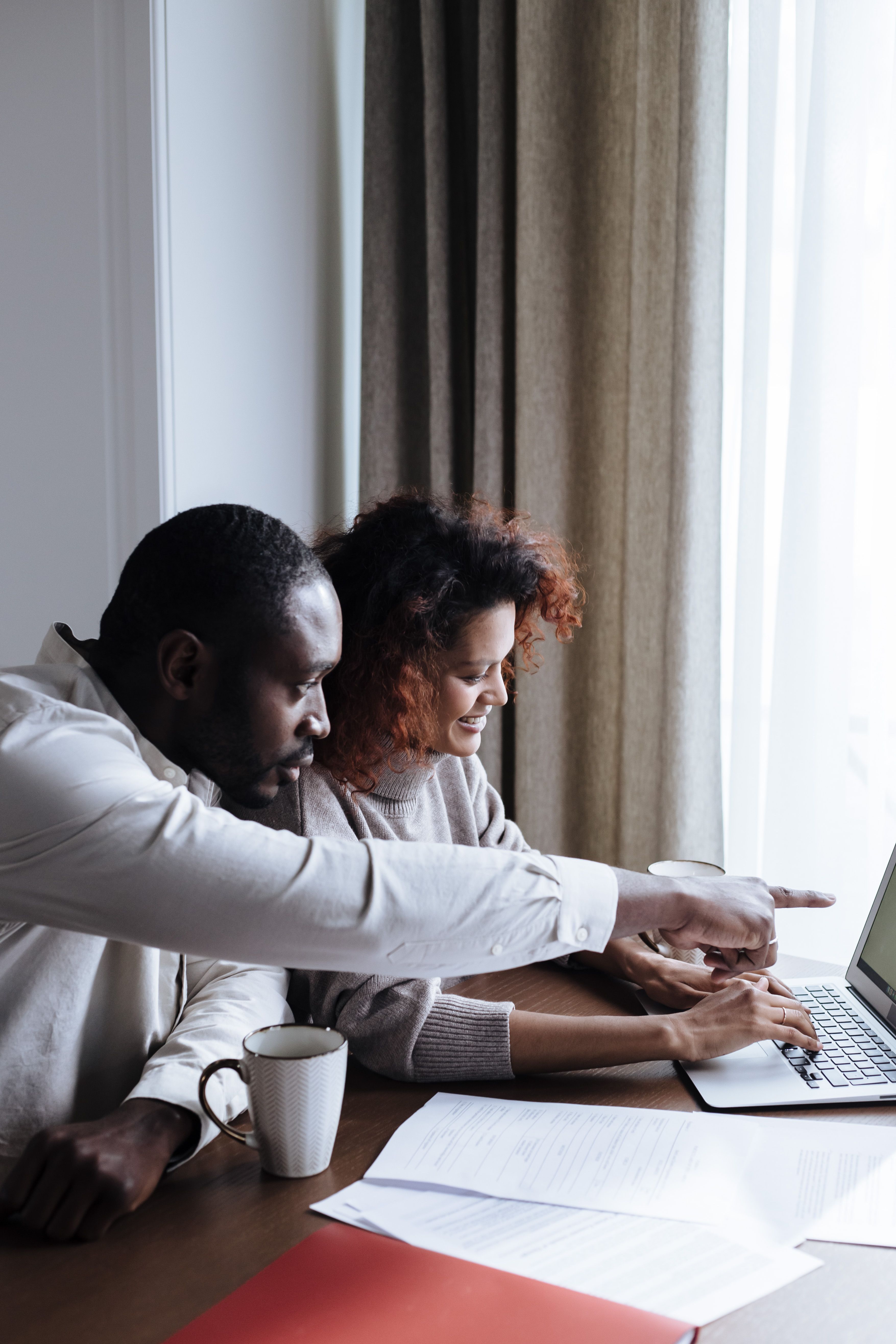 Couple looking at a laptop and paperwork together at home.
