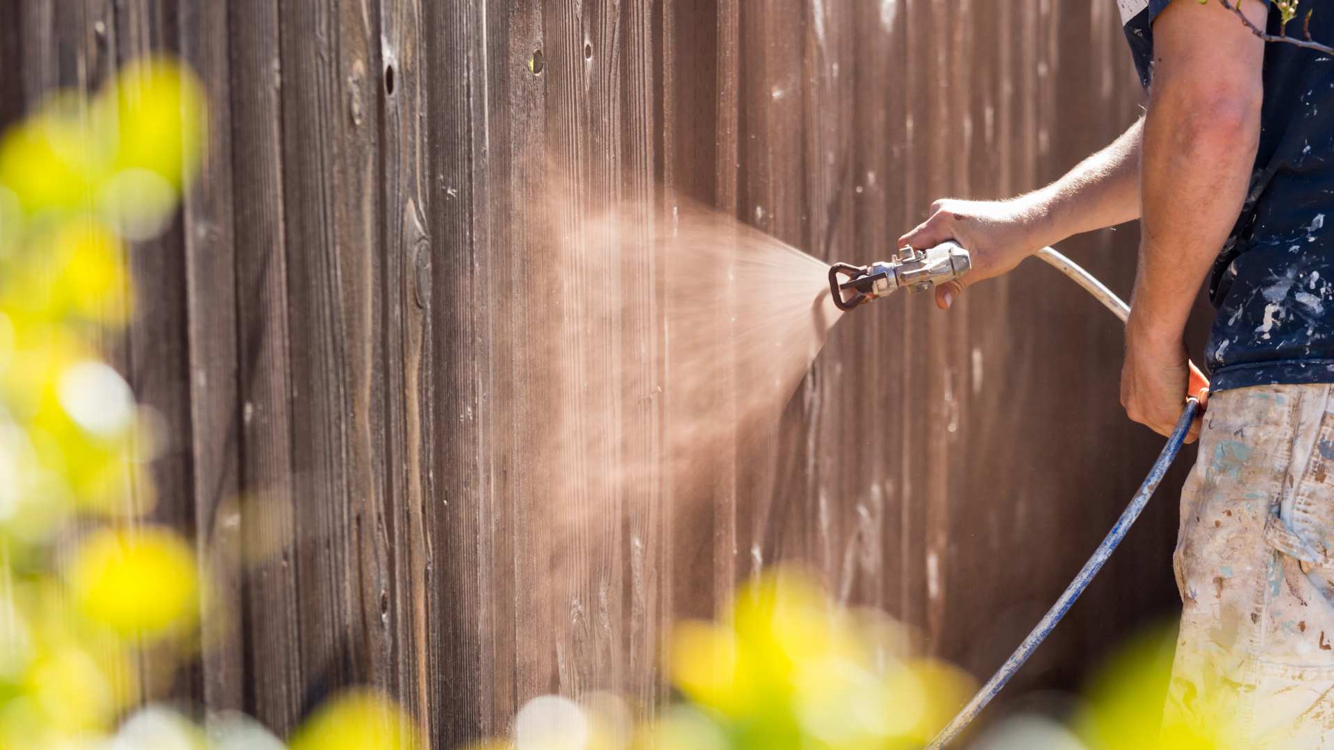 composite fence repaint in progress using spray technique