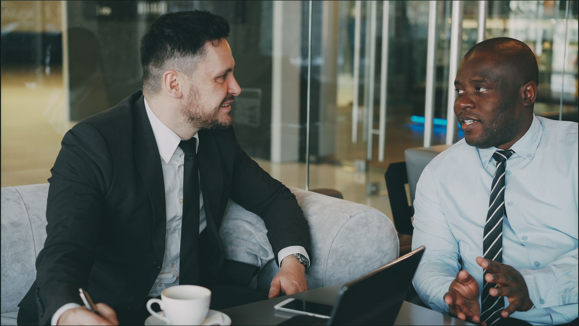 Two business professionals talking together over coffee and a laptop