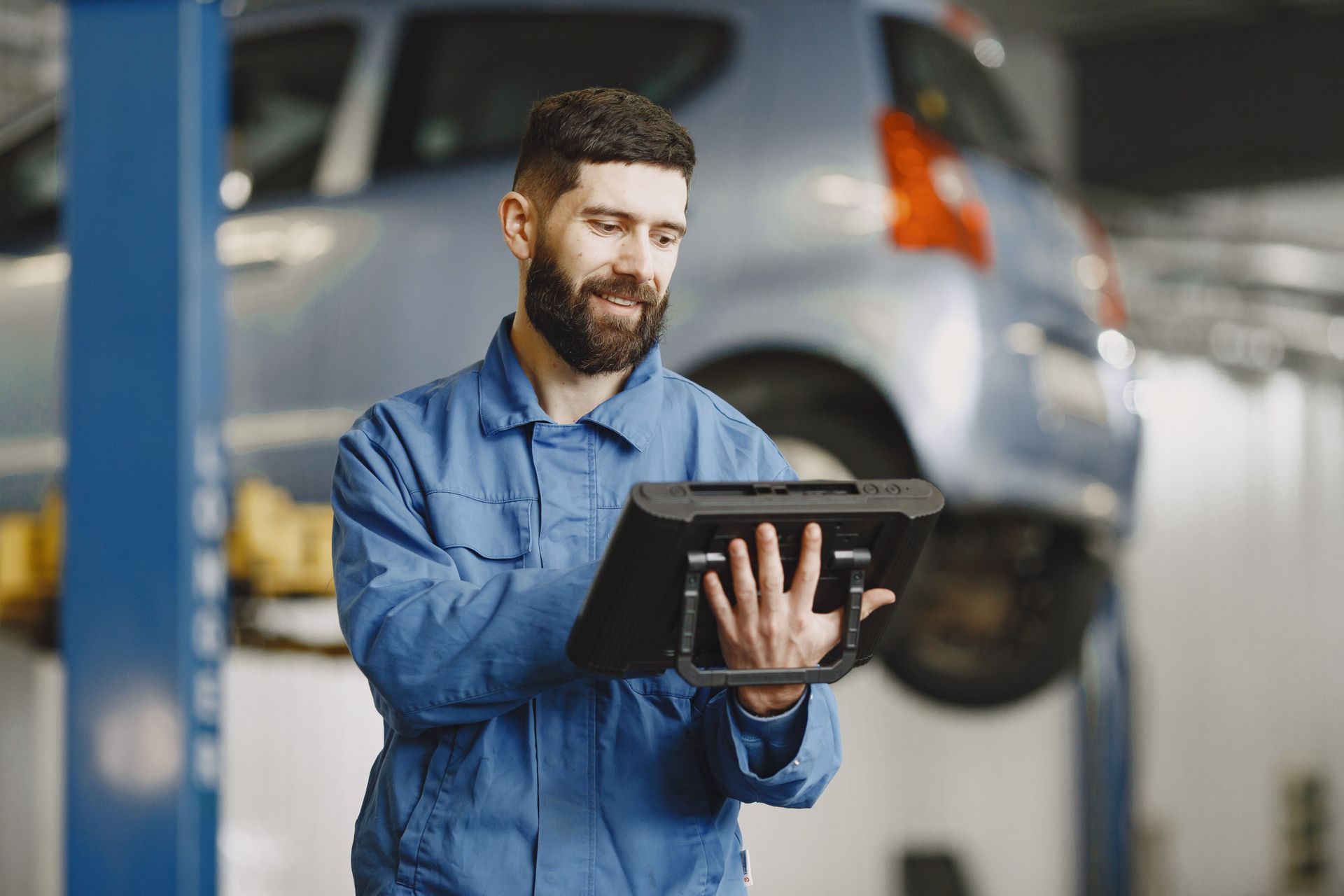 An automotive service professional reviewing a tablet in a repair workshop