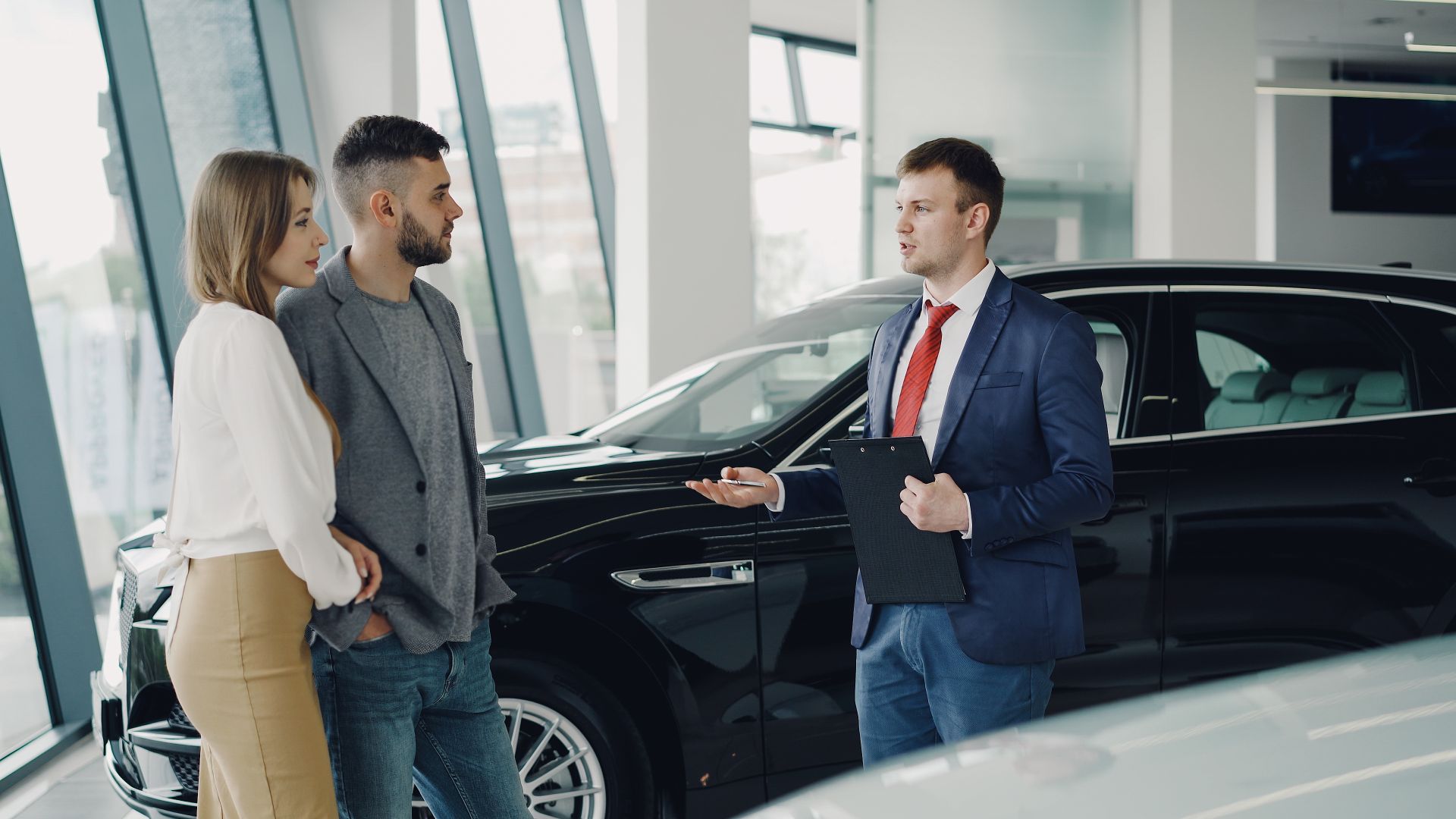 A couple having a conversation with a dealership representative beside a vehicle