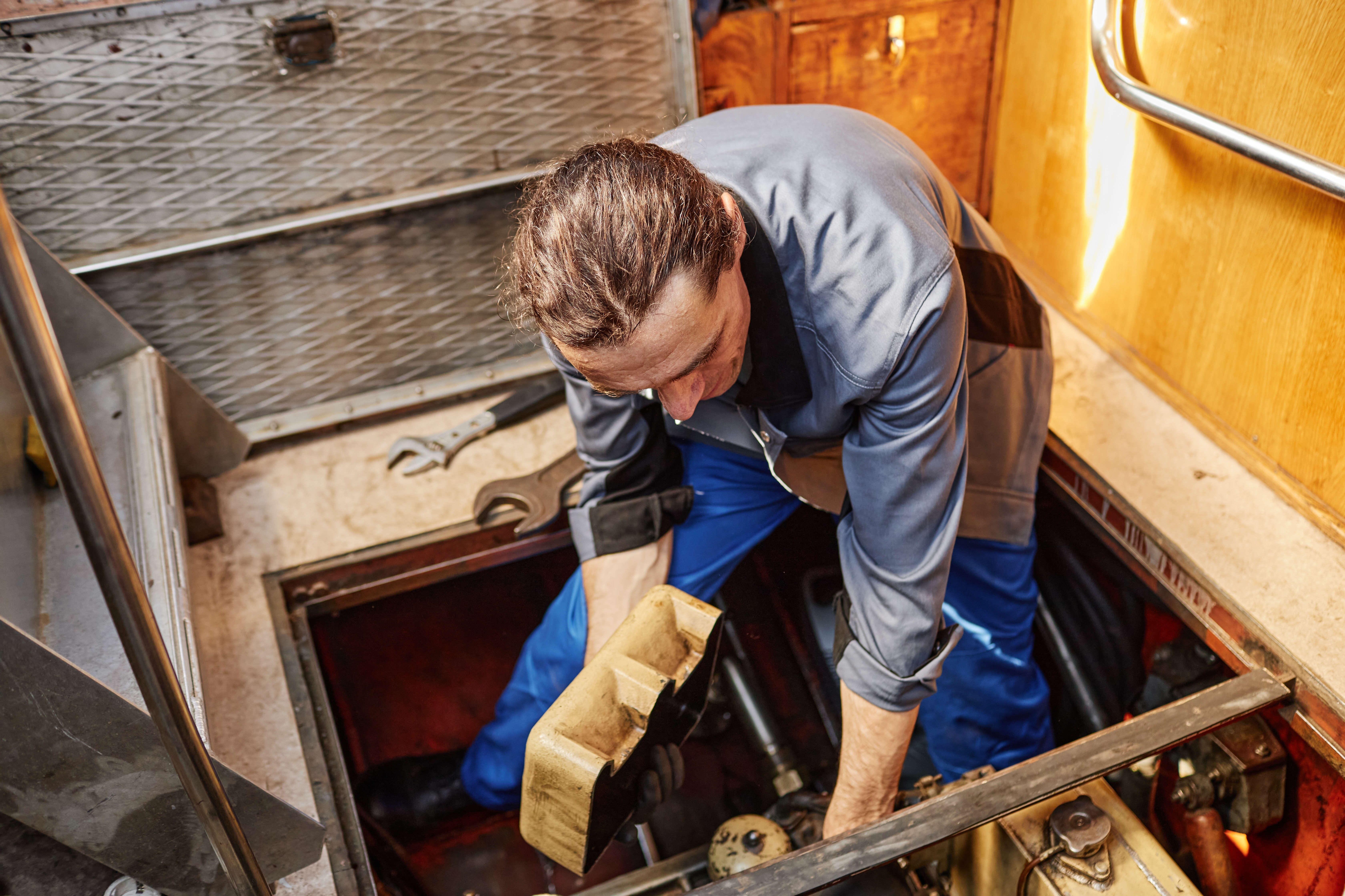Marine technician working in a boat engine compartment