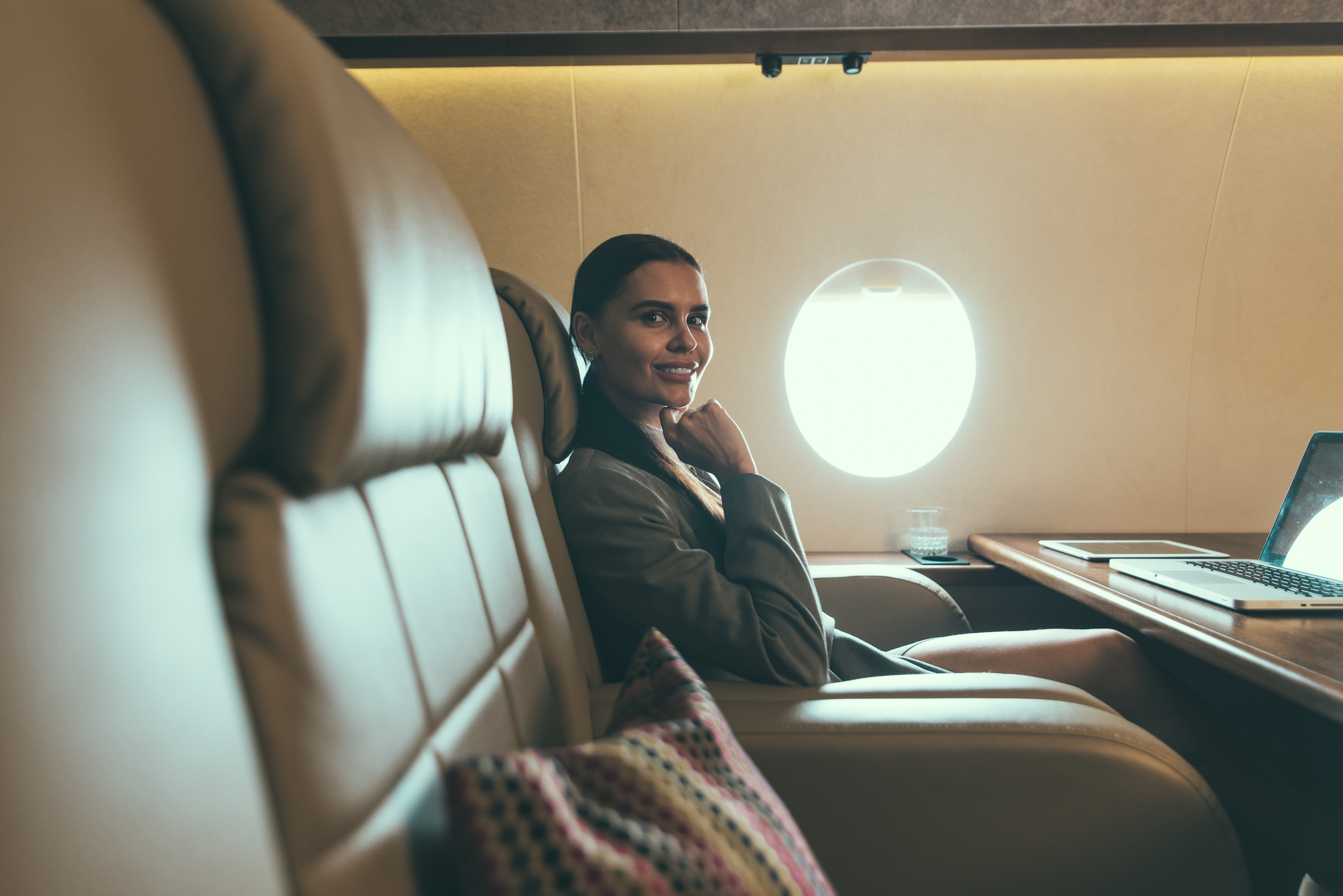 Business traveler seated beside a laptop in a private jet cabin