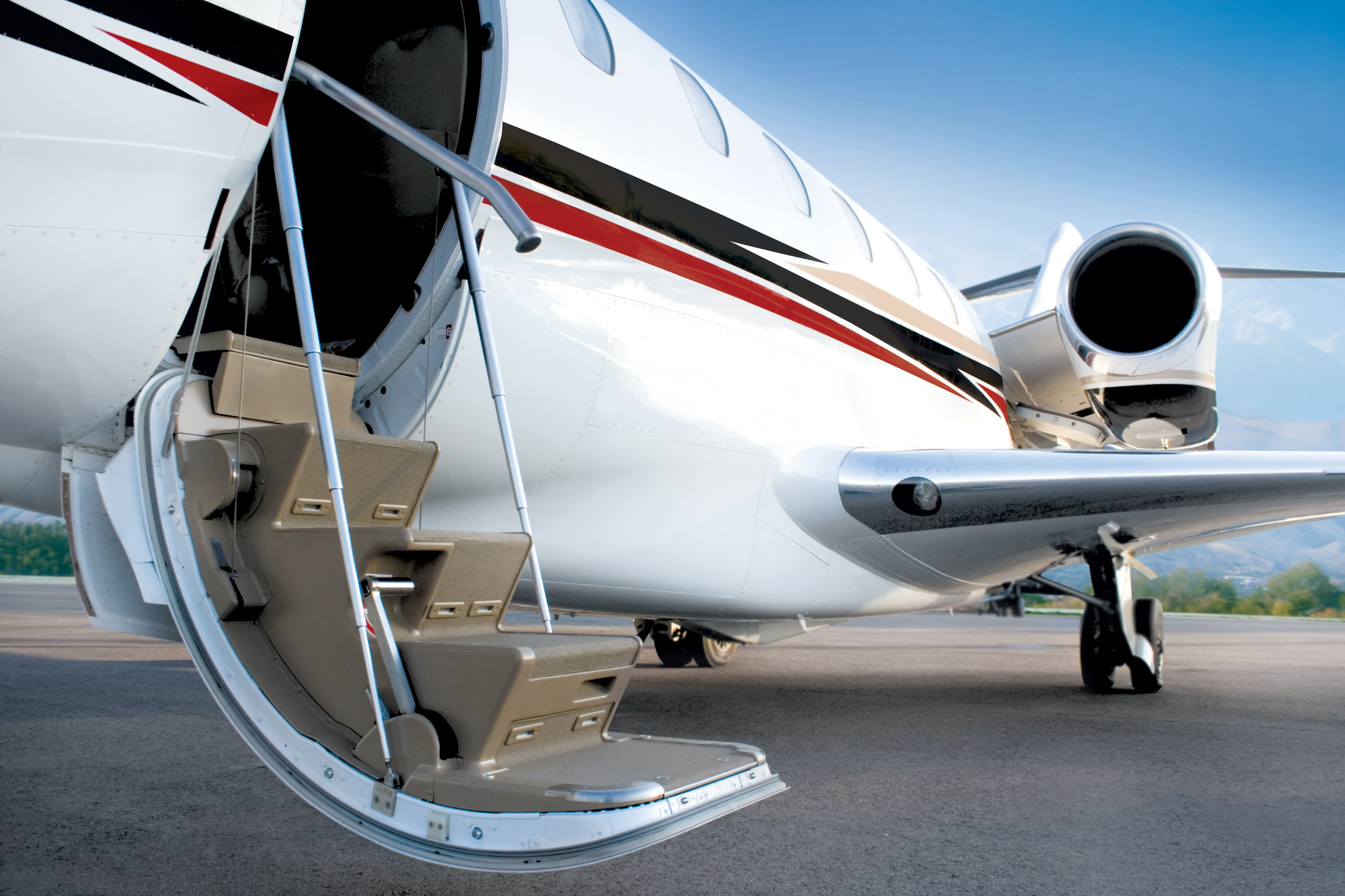 Close view of a private jet with an open cabin door and boarding stairs ready for passengers