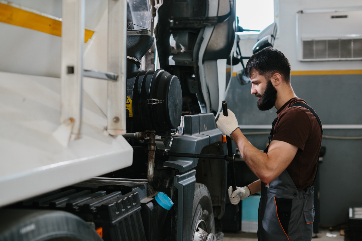 A commercial truck mechanic working beside a tilted truck cab
