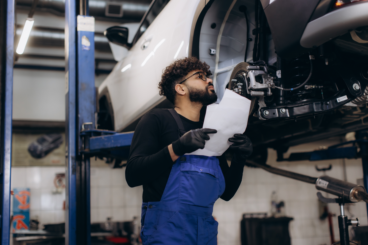 An automotive technician inspecting a vehicle on a workshop lift