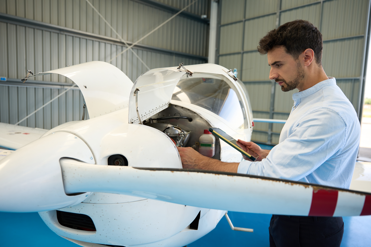 An aircraft technician inspecting a propeller airplane engine in a hangar
