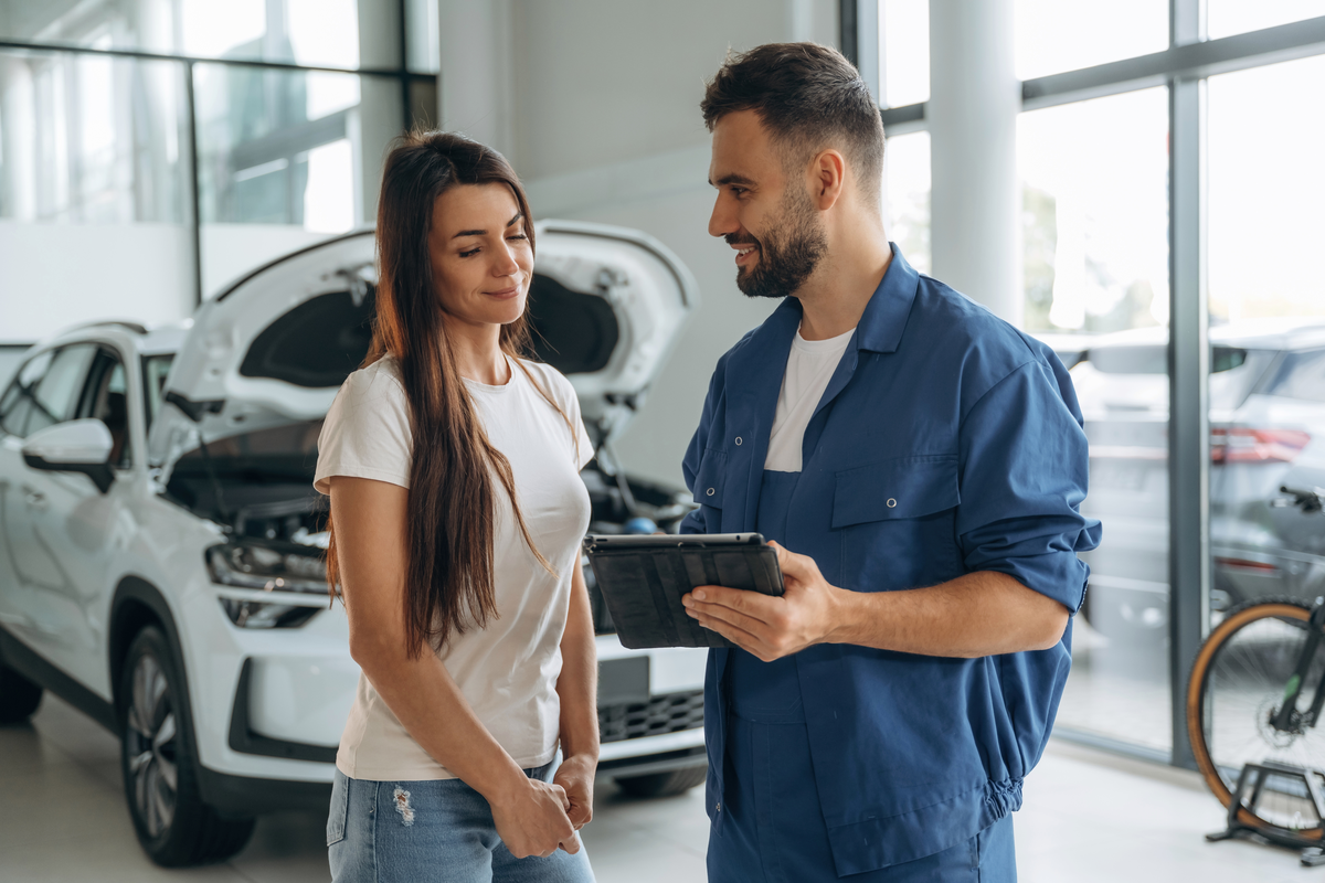 A service advisor and customer reviewing a tablet in an automotive workshop