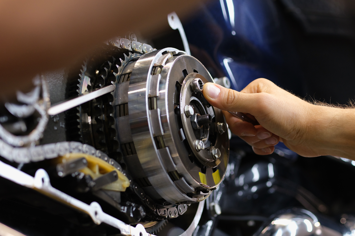 Hands repairing a motorcycle clutch assembly in a workshop