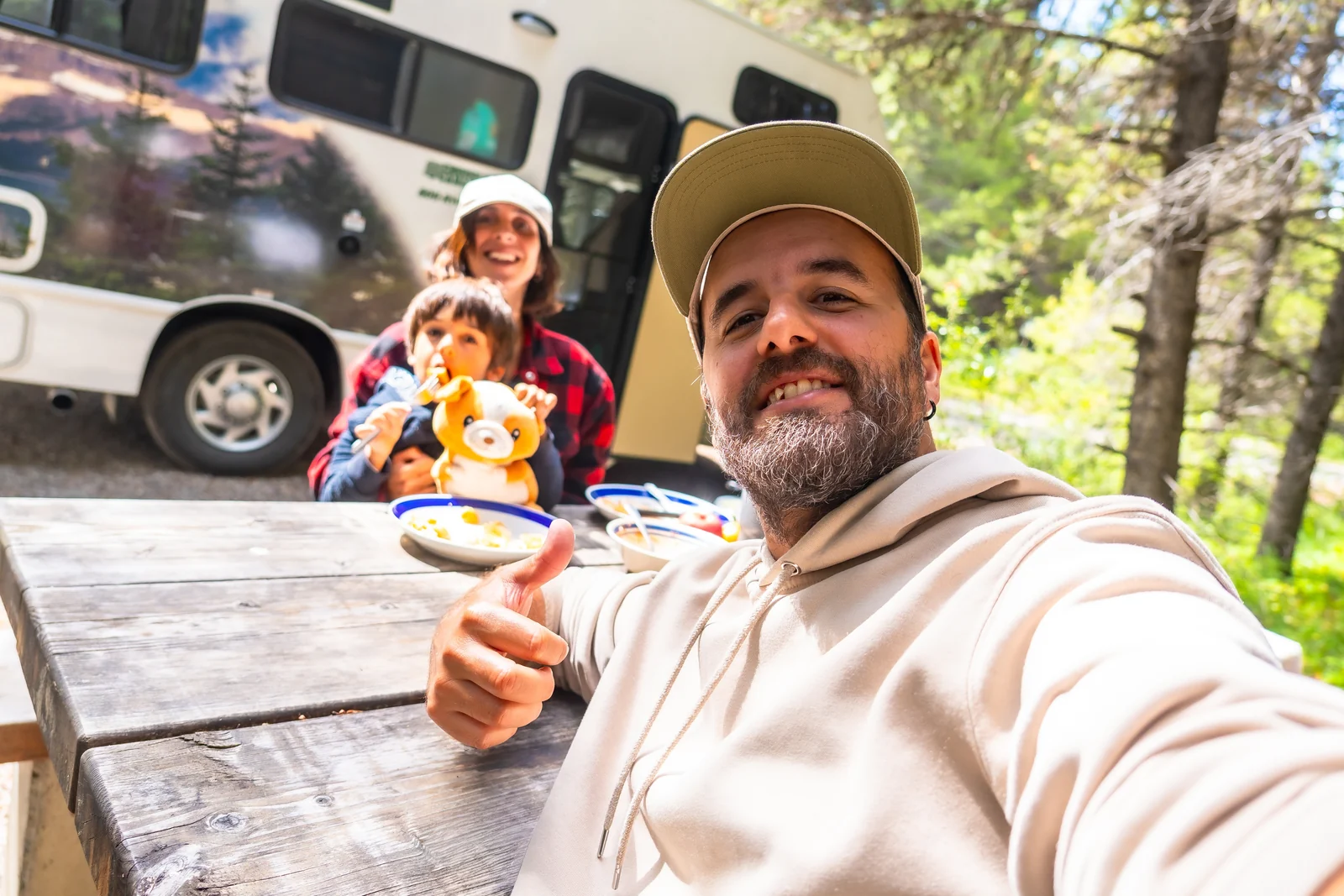 A smiling family enjoying time together beside their RV outdoors.