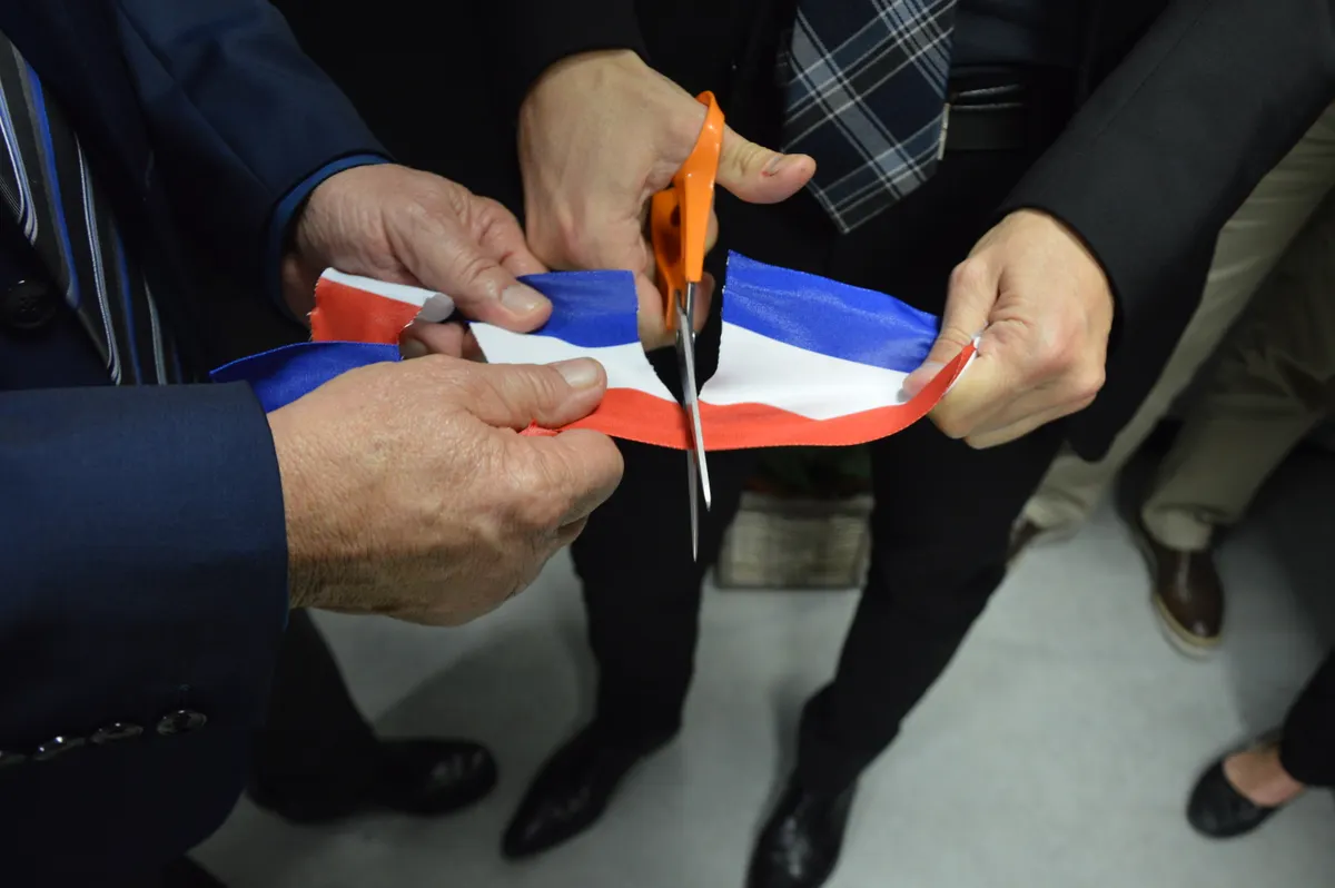 Business representatives cutting a ceremonial ribbon at an opening.