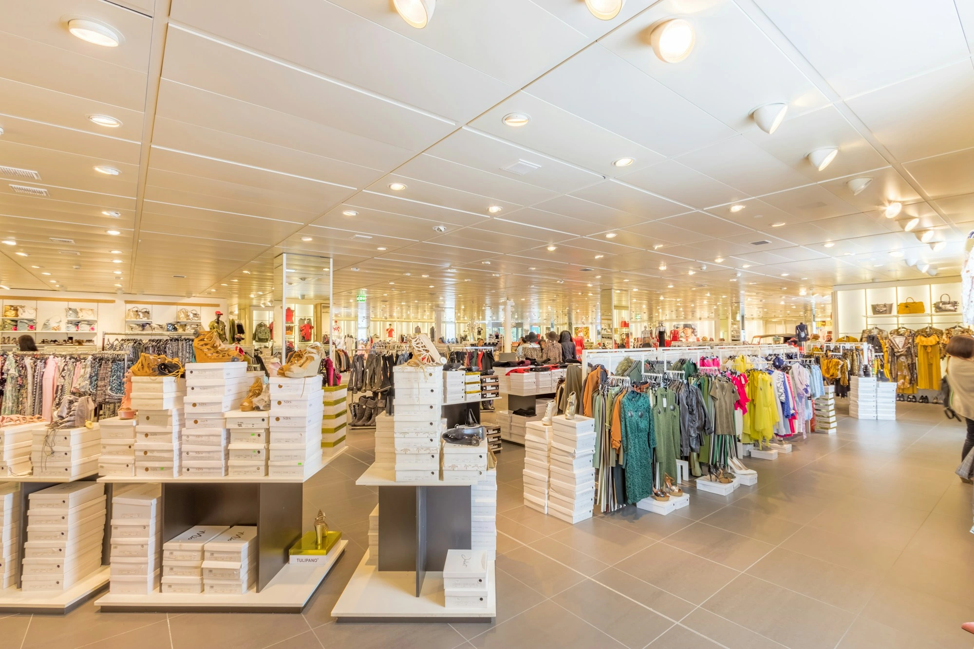 Customers browsing a bright clothing and shoe store during its opening